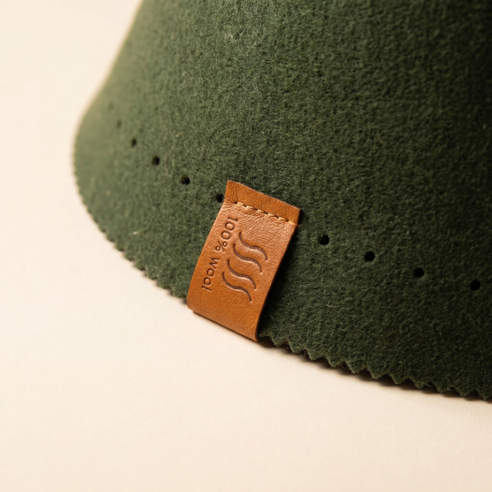 Leather tag on a forest green sauna hat brim, with the pinked felt edge alongside